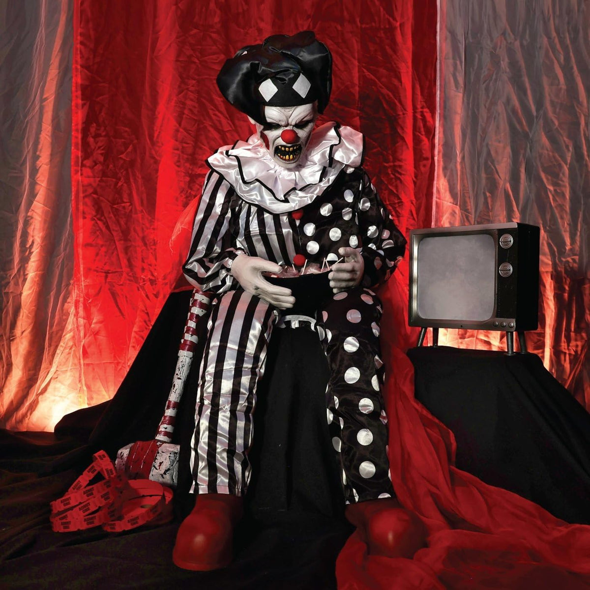 Clown seated in front of red curtains